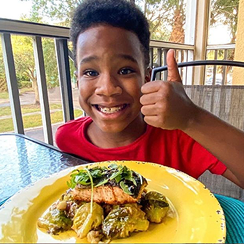 Young boy thumbs up to a salmon dish